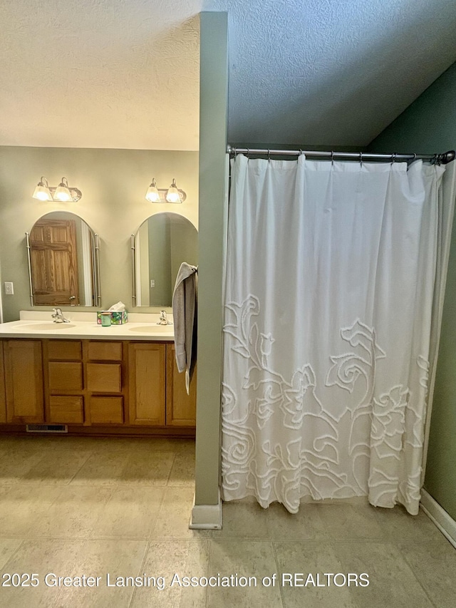 1826 Battle Creek Rd, Charlotte, MI 48813 - full bath with double vanity, baseboards, curtained shower, and a textured ceiling