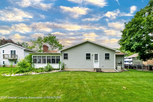 1005 Old Erin Way, Lansing, MI 48917 - back of property with entry steps, a chimney, central AC, and a lawn