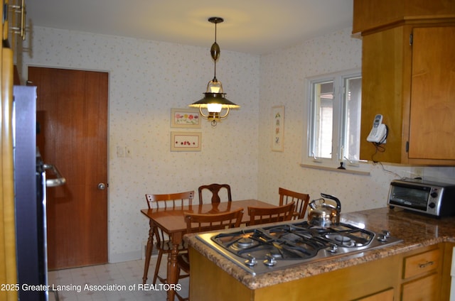 408 Whitehills Dr, East Lansing, MI 48823 - kitchen with stainless steel gas cooktop, wallpapered walls, light floors, pendant lighting, and brown cabinetry