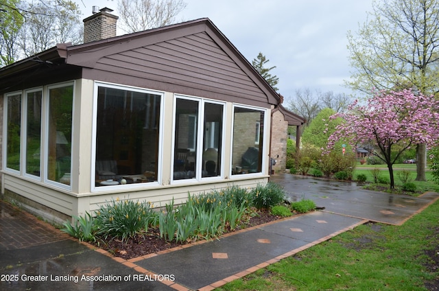 408 Whitehills Dr, East Lansing, MI 48823 - view of side of property with a chimney, a patio area, and a sunroom