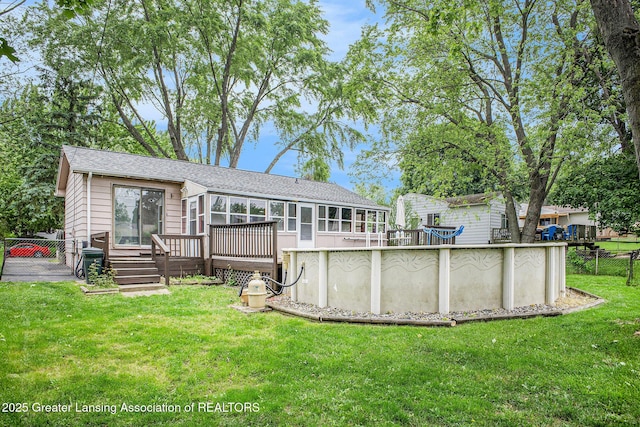 4425 Doncaster Ave, Holt, MI 48842 - back of property with a deck, an outdoor pool, a sunroom, roof with shingles, and a gate