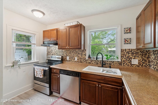 1928 Teel Ave, Lansing, MI 48910 - kitchen with appliances with stainless steel finishes, a sink, under cabinet range hood, healthy amount of natural light, and a textured ceiling