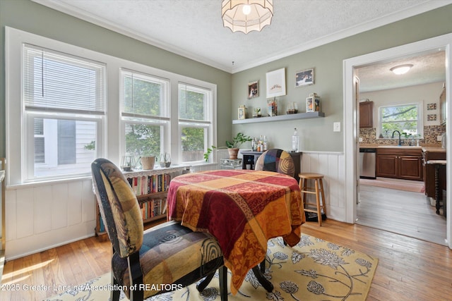 1928 Teel Ave, Lansing, MI 48910 - dining room with light wood-style flooring, a textured ceiling, a wainscoted wall, and ornamental molding
