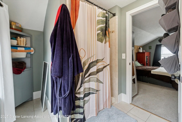 1928 Teel Ave, Lansing, MI 48910 - ensuite bathroom with tile patterned floors, a textured ceiling, vaulted ceiling, a shower with curtain, and baseboards