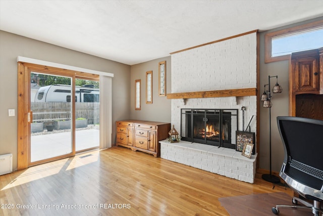 4663 Sycamore St, Holt, MI 48842 - living area featuring a brick fireplace and light wood-style floors