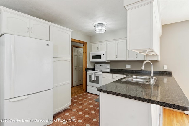 4663 Sycamore St, Holt, MI 48842 - kitchen featuring white appliances, a sink, white cabinets, dark countertops, and a peninsula