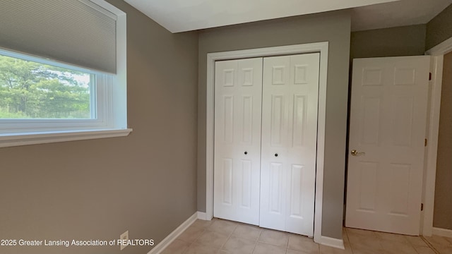 9216 S Grove Rd, Dewitt, MI 48820 - unfurnished bedroom featuring a closet, baseboards, and light tile patterned floors