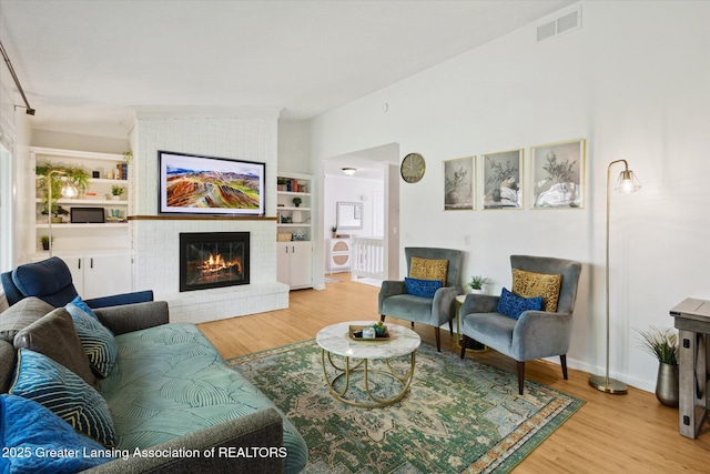1098 Brookside Dr, Grand Ledge, MI 48837 - living area featuring wood finished floors, a fireplace, built in features, lofted ceiling, and baseboards