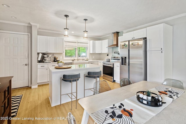 1098 Brookside Dr, Grand Ledge, MI 48837 - kitchen featuring appliances with stainless steel finishes, ornamental molding, light wood-style floors, white cabinets, and a center island