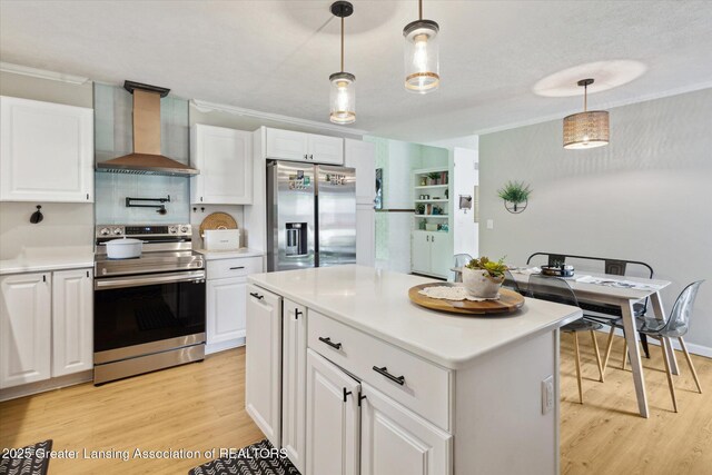 1098 Brookside Dr, Grand Ledge, MI 48837 - kitchen featuring appliances with stainless steel finishes, wall chimney range hood, light wood finished floors, white cabinetry, and ornamental molding