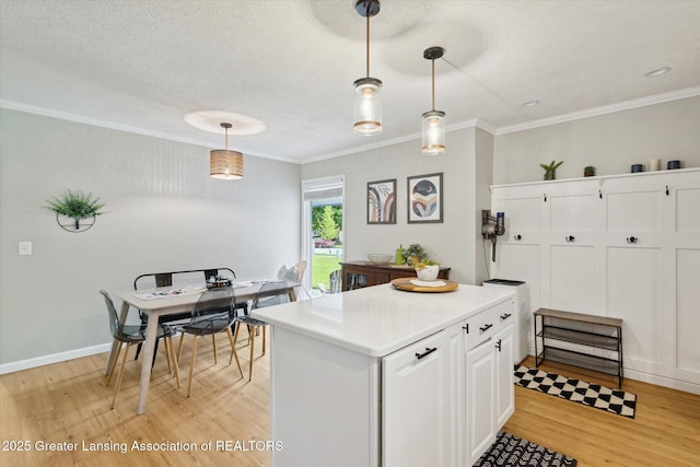 1098 Brookside Dr, Grand Ledge, MI 48837 - kitchen with light wood-style floors, light countertops, hanging light fixtures, ornamental molding, and white cabinets
