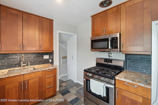 1023 N Hayford Ave, Lansing, MI 48912 - kitchen with stainless steel appliances, a sink, decorative backsplash, and dark stone finish flooring