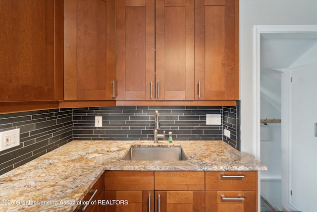 1023 N Hayford Ave, Lansing, MI 48912 - kitchen featuring a sink, decorative backsplash, light stone counters, and brown cabinets
