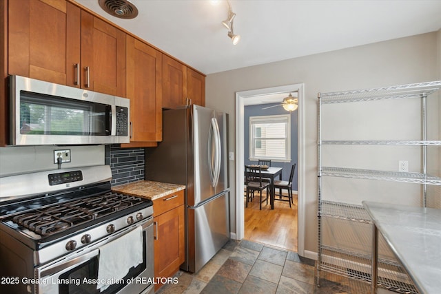 1023 N Hayford Ave, Lansing, MI 48912 - kitchen featuring stainless steel appliances, brown cabinets, light countertops, backsplash, and a ceiling fan