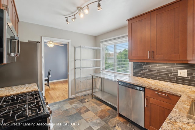 1023 N Hayford Ave, Lansing, MI 48912 - kitchen featuring appliances with stainless steel finishes, brown cabinets, backsplash, a ceiling fan, and light stone countertops