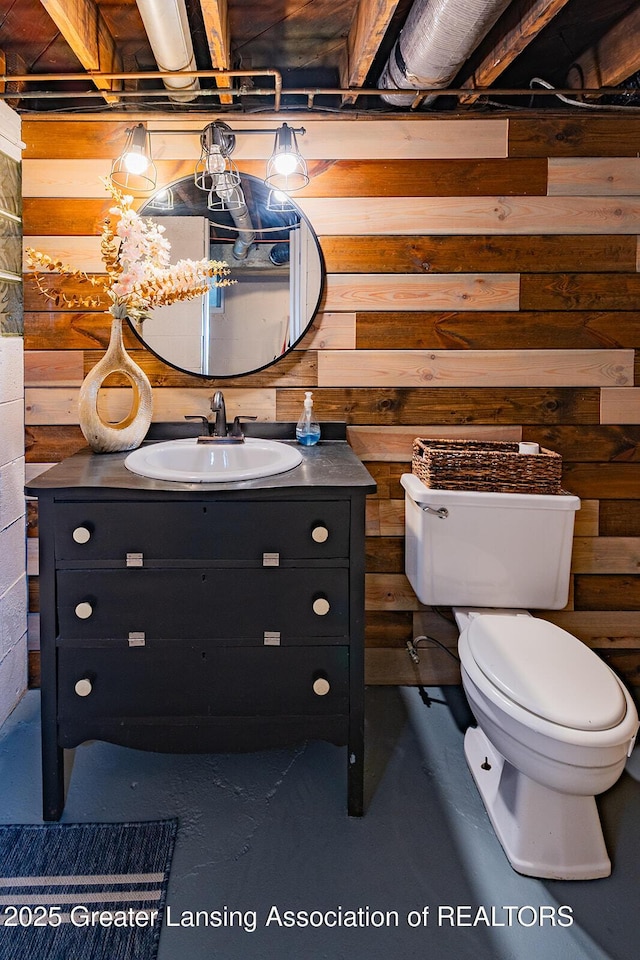 522 W Hodge Ave, Lansing, MI 48910 - half bathroom featuring toilet, concrete flooring, vanity, and wood walls