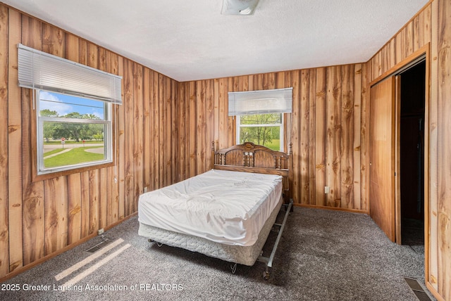 6327 Grovenburg Rd, Lansing, MI 48911 - carpeted bedroom featuring multiple windows, wooden walls, and a textured ceiling