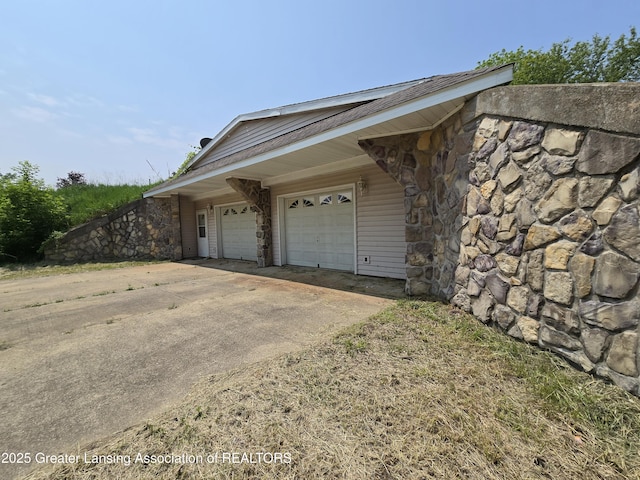 6322 Springport Rd, Eaton Rapids, MI 48827 - view of side of home featuring stone siding, driveway, and an attached garage