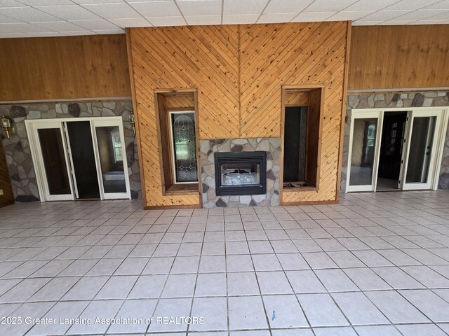 6322 Springport Rd, Eaton Rapids, MI 48827 - unfurnished living room with wood walls, a glass covered fireplace, tile patterned floors, and a paneled ceiling