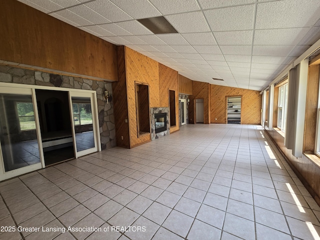 6322 Springport Rd, Eaton Rapids, MI 48827 - unfurnished living room featuring wooden walls, light tile patterned floors, a premium fireplace, and a paneled ceiling
