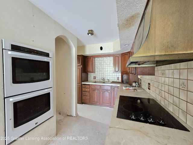 6322 Springport Rd, Eaton Rapids, MI 48827 - kitchen with custom range hood, double oven, black electric cooktop, and light countertops