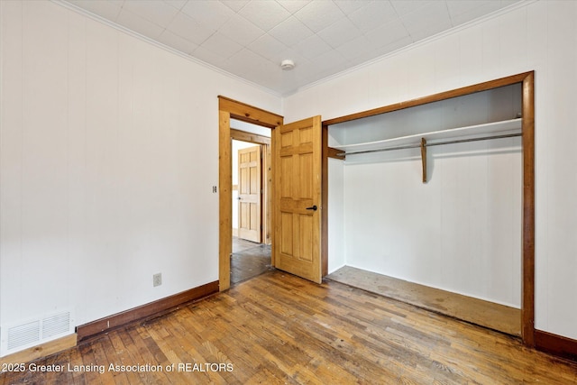 402 W Cesar E Chavez Ave, Lansing, MI 48906 - unfurnished bedroom featuring crown molding, wood-type flooring, and a closet