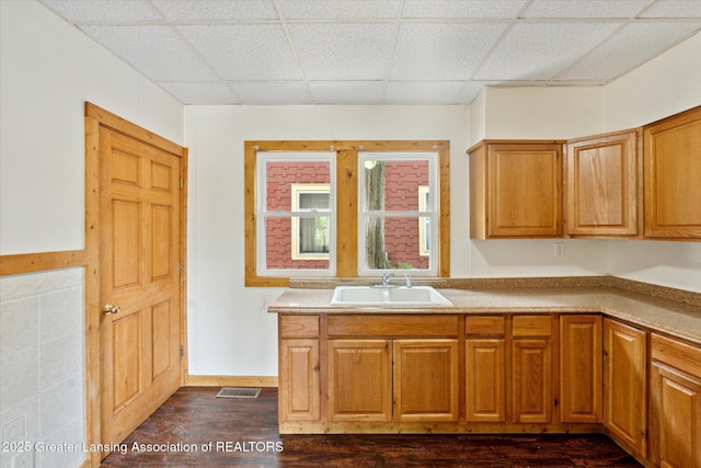 402 W Cesar E Chavez Ave, Lansing, MI 48906 - kitchen with a sink, dark wood-style flooring, a drop ceiling, brown cabinetry, and light countertops