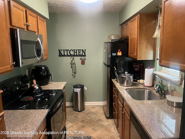 1745 Maisonette Dr, Lansing, MI 48911 - kitchen featuring stainless steel appliances, a textured ceiling, brown cabinetry, a sink, and baseboards