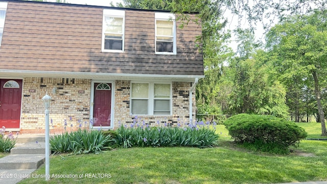 1745 Maisonette Dr, Lansing, MI 48911 - view of front of house featuring a front lawn, covered porch, and brick siding