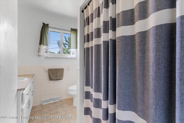 1941 S Royston Rd, Eaton Rapids, MI 48827 - bathroom with tile walls, vanity, toilet, tile patterned flooring, and wainscoting
