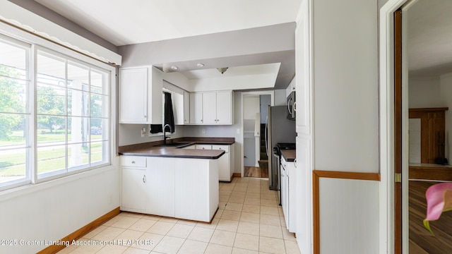 3326 W Willow St, Lansing, MI 48917 - kitchen with a sink, a peninsula, dark countertops, stainless steel appliances, and white cabinets