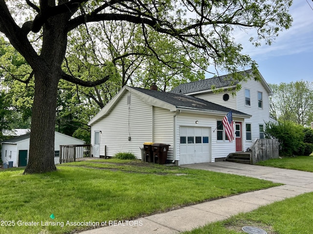 125 N E St, Mason, MI 48854 - view of side of property featuring a garage, a yard, concrete driveway, and a shingled roof