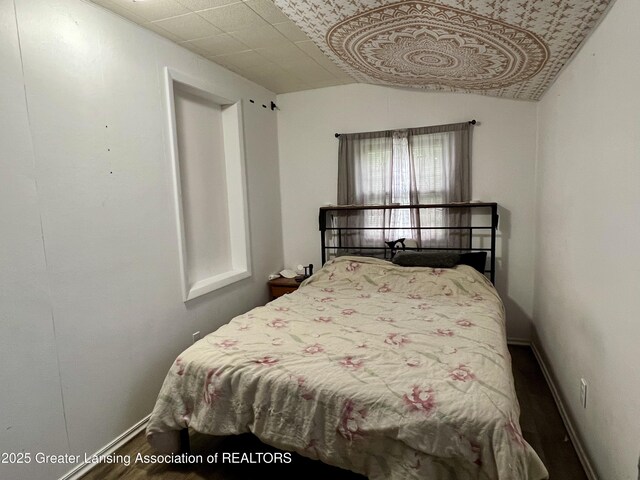 125 N E St, Mason, MI 48854 - bedroom with wood finished floors, vaulted ceiling, and baseboards