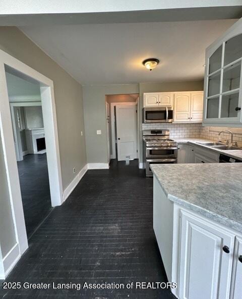 1141 N Genesee Dr, Lansing, MI 48915 - kitchen with stainless steel appliances, a sink, tasteful backsplash, light countertops, and baseboards