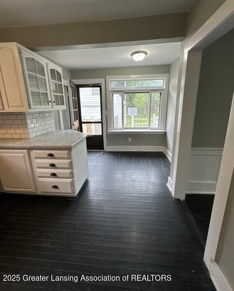 1141 N Genesee Dr, Lansing, MI 48915 - kitchen with glass insert cabinets, light countertops, dark wood-type flooring, backsplash, and white cabinets