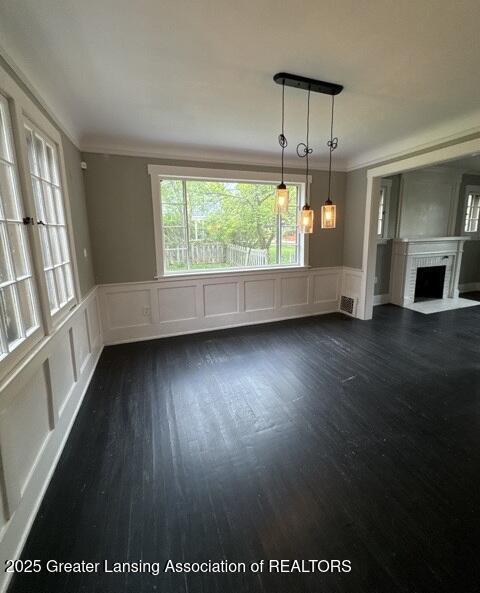 1141 N Genesee Dr, Lansing, MI 48915 - unfurnished living room with a decorative wall, dark wood-style flooring, a fireplace, ornamental molding, and wainscoting