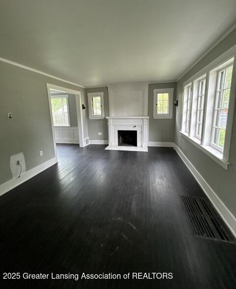 1141 N Genesee Dr, Lansing, MI 48915 - unfurnished living room featuring plenty of natural light, a fireplace with flush hearth, and dark wood-style flooring