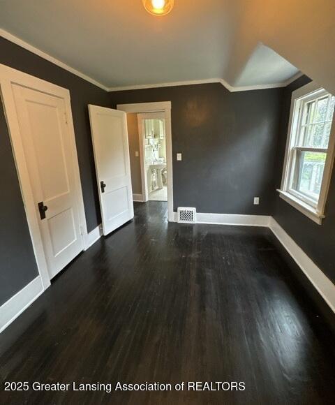 1141 N Genesee Dr, Lansing, MI 48915 - empty room featuring baseboards, dark wood-style floors, ornamental molding, and lofted ceiling