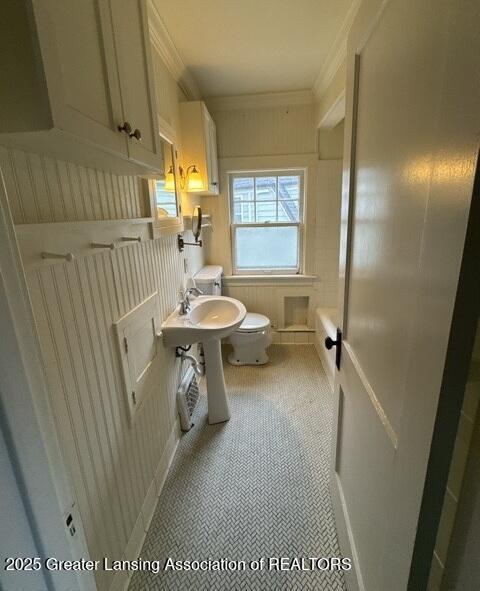 1141 N Genesee Dr, Lansing, MI 48915 - half bathroom featuring toilet, ornamental molding, and tile patterned floors