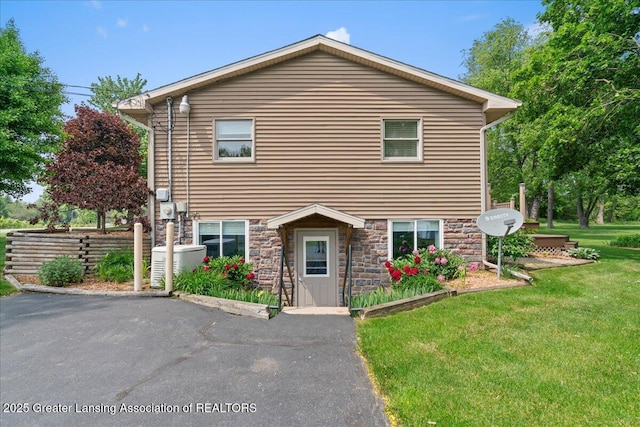 1055 Hull Rd, Mason, MI 48854 - view of front of house featuring a front yard, stone siding, and central AC