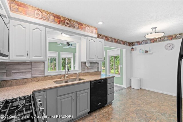 1055 Hull Rd, Mason, MI 48854 - kitchen with black dishwasher, a sink, a ceiling fan, range with gas stovetop, and backsplash
