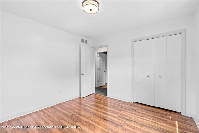 1055 Hull Rd, Mason, MI 48854 - unfurnished bedroom featuring wood finished floors, a closet, and baseboards