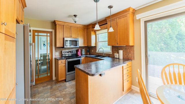 120 Chanticleer Trl, Lansing, MI 48917 - kitchen with stainless steel appliances, a sink, dark countertops, a peninsula, and decorative backsplash