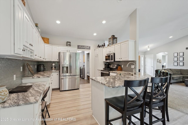 11782 Sara Ann Dr, Dewitt, MI 48820 - kitchen featuring stainless steel appliances, a peninsula, a breakfast bar, light wood-type flooring, and recessed lighting