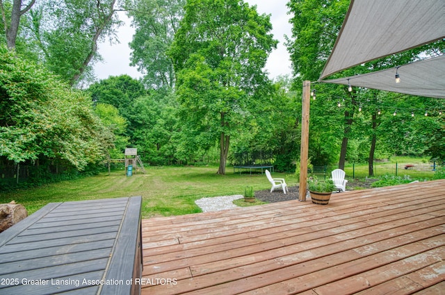 5013 Algonquin Way, Okemos, MI 48864 - deck featuring a trampoline, a playground, a yard, and view of scattered trees