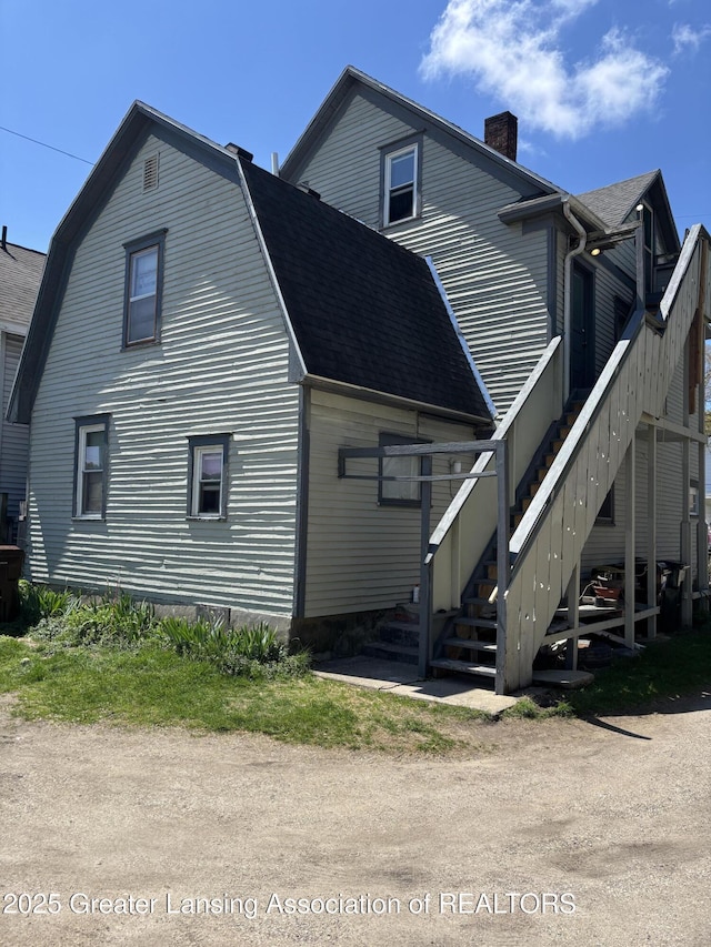 1417 Reo Ave, Lansing, MI 48910 - rear view of house featuring a chimney, stairway, a gambrel roof, and roof with shingles