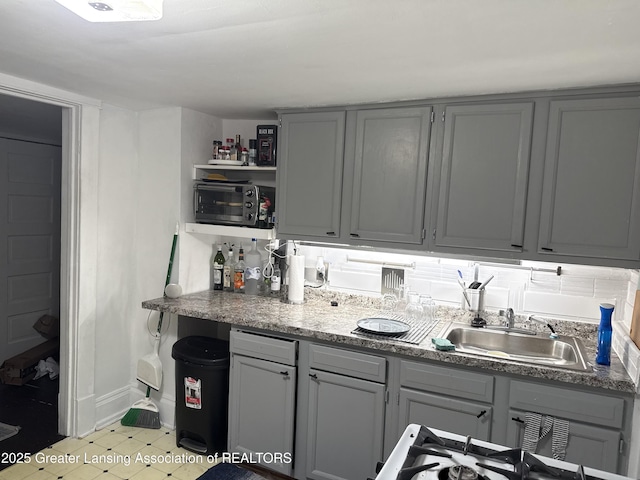 1417 Reo Ave, Lansing, MI 48910 - kitchen with a sink, gray cabinets, open shelves, baseboards, and stovetop
