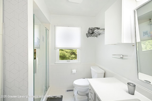 2038 Woodfield Rd, Okemos, MI 48864 - bathroom with tile walls, toilet, vanity, a shower stall, and a wainscoted wall