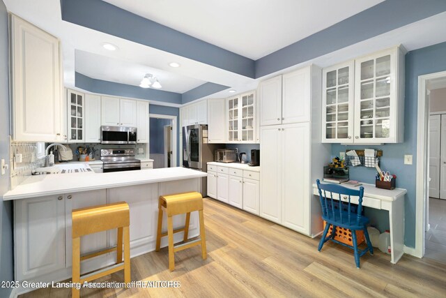 2038 Woodfield Rd, Okemos, MI 48864 - kitchen with appliances with stainless steel finishes, a sink, light wood-style flooring, a peninsula, and recessed lighting