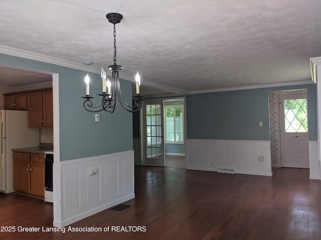 15632 Park Lake Rd, East Lansing, MI 48823 - unfurnished dining area with dark wood finished floors, a chandelier, wainscoting, ornamental molding, and a textured ceiling